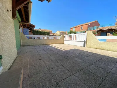 a patio with a white fence and a building at Maison climatisée front de plage du Grazel GA080-086 in Gruissan