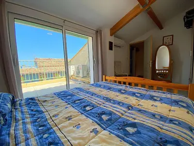 a bedroom with a bed and a large window at Maison climatisée front de plage du Grazel GA080-086 in Gruissan