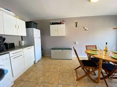 a kitchen with a table and a table and chairs at Maison climatisée front de plage du Grazel GA080-086 in Gruissan