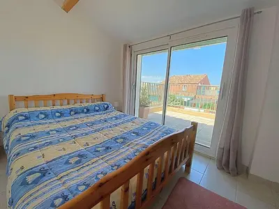 a bedroom with a bed and a large window at Maison climatisée front de plage du Grazel GA080-086 in Gruissan