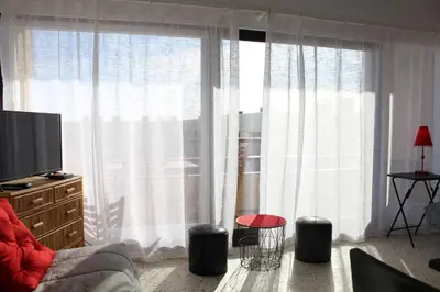a living room with a large window with white curtains at Appartement studio PORT LA NOUVELLE PN590-014 in Port-la-Nouvelle