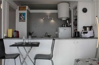 a kitchen with a counter and a table with two chairs at Appartement studio PORT LA NOUVELLE PN590-014 in Port-la-Nouvelle