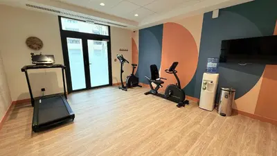 a gym with exercise bikes and a flat screen tv at DOMITYS - Carmina in Carcassonne