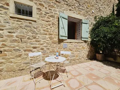 a table and two chairs in front of a stone building at Belle Bize in Bize-Minervois