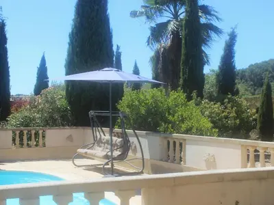 a chair with an umbrella next to a swimming pool at Belle Bize in Bize-Minervois