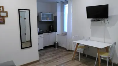 a small kitchen with a table and a tv on a wall at RDC cosy en centre ville in Narbonne
