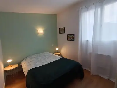 a bedroom with a bed and two tables with lamps at LA FALAISE - Quiet T3 apartment with private parking in Caucalières