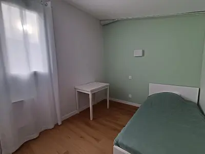 a small bedroom with a bed and a table at LA FALAISE - Quiet T3 apartment with private parking in Caucalières