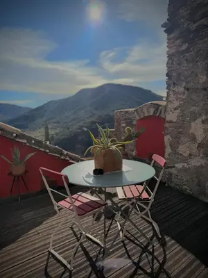 a table and chairs on a balcony with a plant at Ostal de la Croix Vieussan in Vieussan