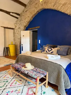 a bedroom with a large bed with a blue wall at Ostal de la Croix Vieussan in Vieussan