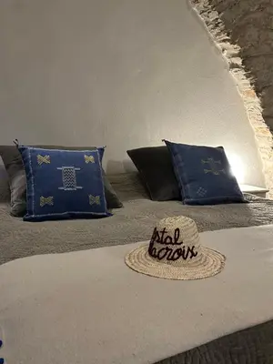 a bed with two pillows and a hat on it at Ostal de la Croix Vieussan in Vieussan