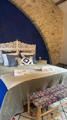 a bedroom with a large bed with a stone wall at Ostal de la Croix Vieussan in Vieussan