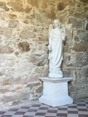 a statue of a woman standing in front of a stone wall at Château de Villeneuve - Montolieu in Montolieu