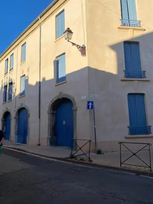 a building with blue doors on a street at Appartement RDC avec cour privée - Narbonne Les Halles Centre Historique in Narbonne