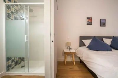 a bedroom with a bed and a glass shower at L'Hippocrate Duplex à deux pas des Halles in Narbonne