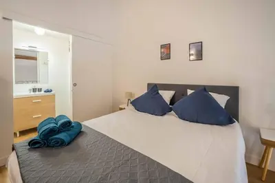 a bedroom with a large bed with blue pillows at L'Hippocrate Duplex à deux pas des Halles in Narbonne