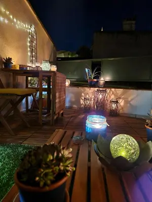 a wooden deck with a table with plants and lights at Very charming village house in Capendu