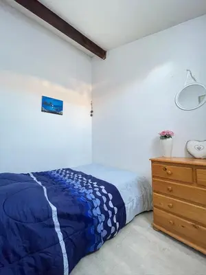 a bedroom with a blue bed and a wooden dresser at Maison avec piscine clim parking in Leucate