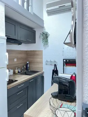 a kitchen with gray cabinets and a black chair at Maison avec piscine clim parking in Leucate