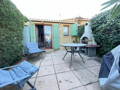 a patio with a table and chairs and a fireplace at Maison avec piscine clim parking in Leucate