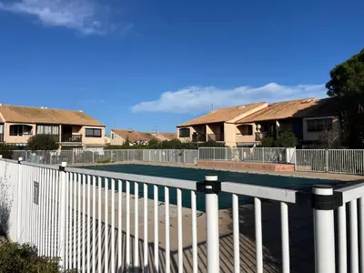 a tennis court in front of some houses at Maison avec piscine clim parking in Leucate