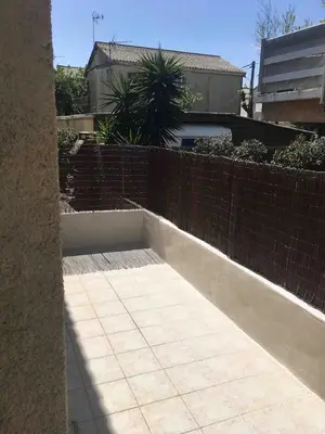 a patio with a brick fence and a sidewalk at Plage des Chalets in Gruissan