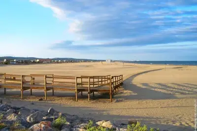 two benches sitting on a beach near the ocean at Plage des Chalets in Gruissan