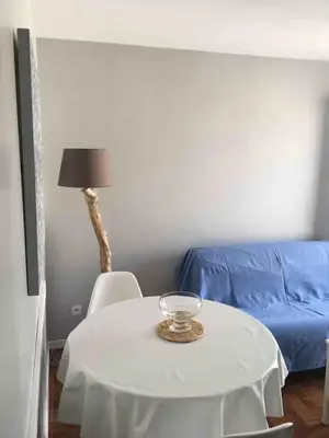 a living room with a table and a blue couch at Plage des Chalets in Gruissan