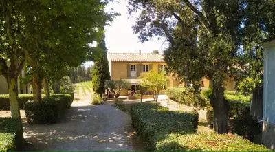 a yellow house with trees and a driveway at Bergerie de L'horte in Tourouzelle
