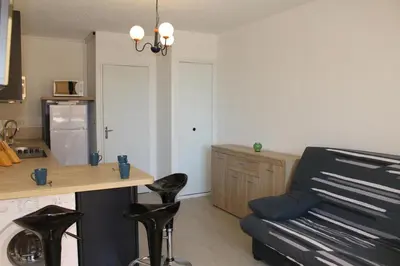 a kitchen with a table and chairs and a couch at Appartement calme avec piscine commune et loggia GN050-489 in Gruissan