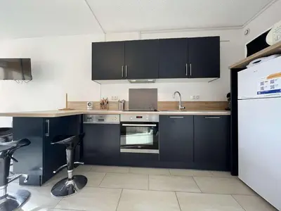 a kitchen with black cabinets and a white refrigerator at Appartement calme avec piscine commune et loggia GN050-489 in Gruissan