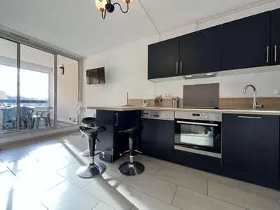 a kitchen with black cabinets and a counter with stools at Appartement calme avec piscine commune et loggia GN050-489 in Gruissan