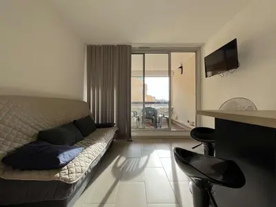 a bedroom with a bed and a living room with a balcony at Appartement calme avec piscine commune et loggia GN050-489 in Gruissan