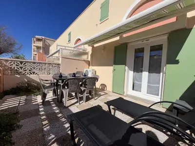 a patio with a table and chairs in front of a house at Maison 3 pièces - Gruissan GN500-022 in Gruissan