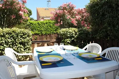 a white table with chairs and plates and glasses on it at Maison studio mezzanine avec parking privé GN020-095 in Gruissan