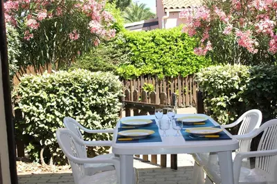 a white table and chairs with plates and glasses on it at Maison studio mezzanine avec parking privé GN020-095 in Gruissan