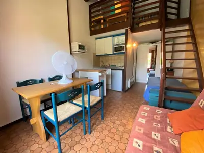 a kitchen and dining room with a table and a bunk bed at Maison studio mezzanine avec parking privé GN020-095 in Gruissan