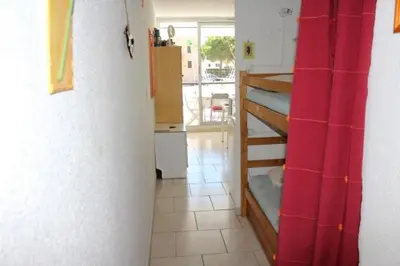 a kitchen with a room with bunk beds and a red curtain at Appartement cosy avec vue et piscine sur le port - GN400-013 in Gruissan