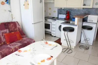 a kitchen with a table and a couch and a table and chairs at Appartement cosy avec vue et piscine sur le port - GN400-013 in Gruissan