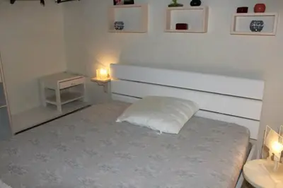 a white bedroom with a bed and a nightstand with two lights at Appartement cosy avec vue et piscine sur le port - GN400-013 in Gruissan