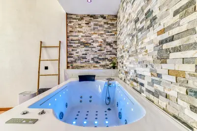 a blue tub in a room with a brick wall at Parenthèse Occitane - Free Parking - Balnéothérapie in Carcassonne