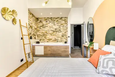 a bedroom with a bed and a bathroom with a tub at Parenthèse Occitane - Free Parking - Balnéothérapie in Carcassonne