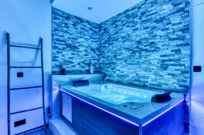 a bathroom with a tub with a brick wall at Parenthèse Occitane - Free Parking - Balnéothérapie in Carcassonne