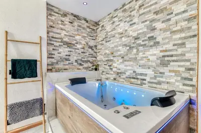 a bath tub in a bathroom with a brick wall at Parenthèse Occitane - Free Parking - Balnéothérapie in Carcassonne