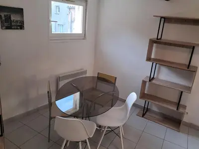 a dining room with a glass table and white chairs at le duplex charmant et cosy in Narbonne