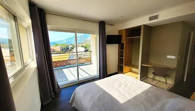 a bedroom with a bed and a large window at DOMAINE LA TOUPIE Chambres d'hôtes in Maury