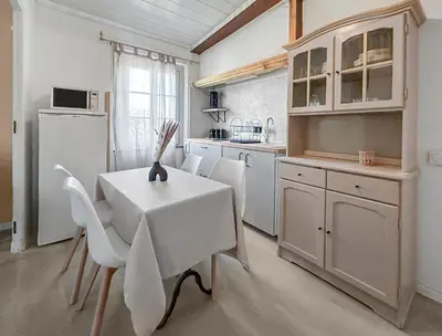 a kitchen with a table and chairs and a refrigerator at T2 Cosy Vue Sur La Cité in Carcassonne