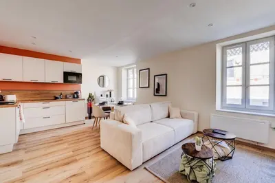 a living room with a white couch and a kitchen at Chez Seb - Raffiné et Accueillant in Carcassonne