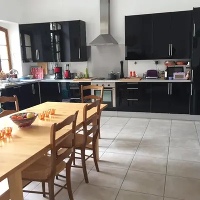 a kitchen with a wooden table and chairs at Stylish large house with heated pool in historic village in Bize-Minervois
