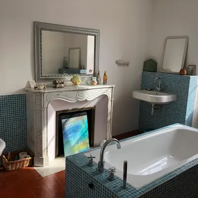 a bathroom with a fireplace and a tub and a sink at Stylish large house with heated pool in historic village in Bize-Minervois